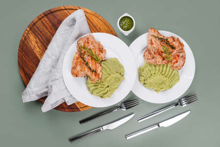 Delicious grilled chicken with herbs and green puree. Chicken fillet with mashed potatoes, green peas and pesto sauce. Healthy homemade food. Flat lay, top viewの写真素材