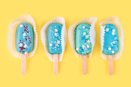 Blue mint ice creams on yellow background. Tasty and refreshing ice cream on sticks. Minimal summer concept. Flat layの写真素材