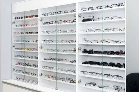 Eyeglasses in optical store, fashion, different glasses on white shelf in shopping mall. Selective focus.の写真素材