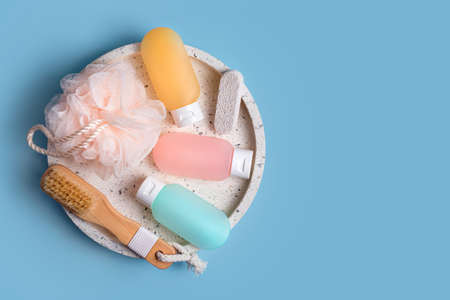 Cosmetic products for spa and bath accessories on blue background. Colorful plastic containers for...