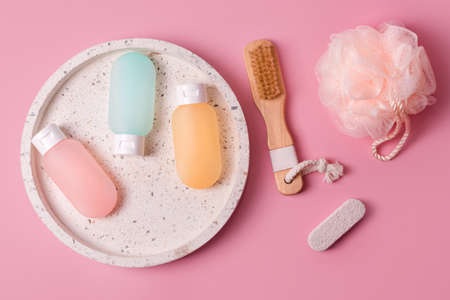 Cosmetic products for spa and bath accessories on pink background. Colorful plastic containers for...