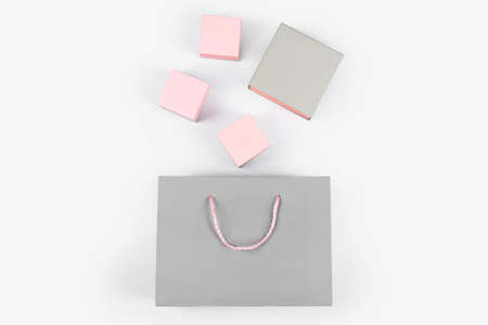 Gray paper shopping bag and pink gift boxes on light background. Free space for text. Shopping, sale, surprise or gift concept.の写真素材