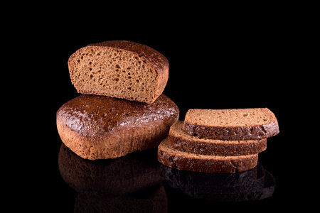 Freshly baked homemade bread isolated on black. Cut in half rye bread with slices. Healthy eating...