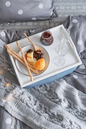 Breakfast in bed, a tray with cheese, grissini, jam from young fir cones and a candle. Christmas...