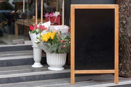 Signboard on the street. Empty menu board stand. Restaurant sidewalk chalkboard sign board. Freestanding A-frame blackboard near flower shop. Copyspace for text, selective focus.の写真素材