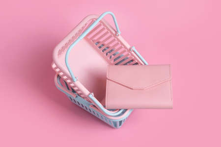 Colorful plastic shopping baskets with leather wallet. Empty pink and blue supermarket baskets on pink pastel background. Creative design, shopping, black friday, discount, advertising, sale conceptの写真素材