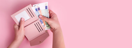 Hands holding wallet. Pink leather wallet with euro money in female hands. Closeup on a woman's hands taking European bank notes out of purse. Concept of money, finances, shopping, cash, banner.の写真素材