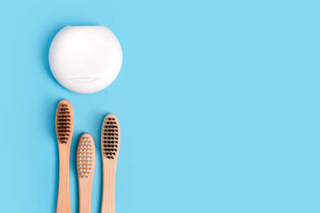 Dental floss containers and bamboo toothbrushes on blue background. Daily oral hygiene, teeth care and health. Cleaning products for mouth. Dental care concept. Empty place for text or logo.の写真素材