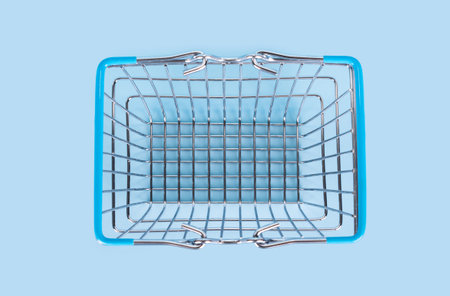 Top view of supermarket shopping basket on light blue background. Empty metal wire supermarket basket. Black friday, sale, shopping concept. Sustainable lifestyleの写真素材