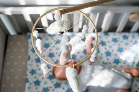 Baby crib mobile with smiling clouds and snow. Kids handmade toys above the newborn crib. First baby...