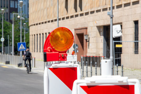 Red and white street barriers with flashlight to secure a construction site, roadworks, road under construction. Temporary fencing, repair on the city street, closed for renovation. No way, stop and detour signの写真素材