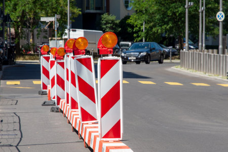 Red and white street barriers with flashlight to secure a construction site, roadworks, road under construction. Temporary fencing, repair on the city street, closed for renovation. No way, stop and detour signの写真素材