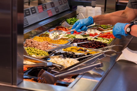 Choosing food from buffet. Fresh salad bar with a variety of fresh vegetables, vegetable table for...