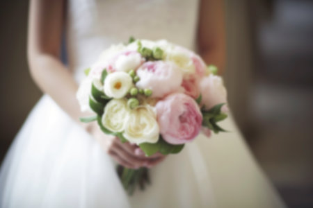 Blurred wedding day background, bride holding a wedding bouquet, copy space for text, wedding card or invitation template. AI generatedの素材