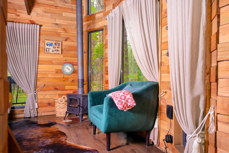 A cozy wooden cabin interior featuring a stove, comfortable seating, and spacious windows framing a...