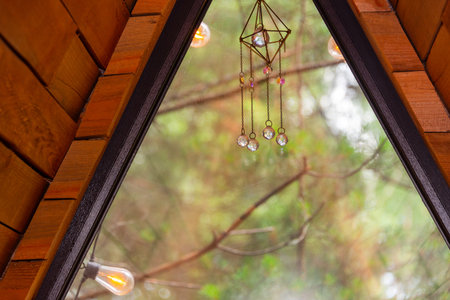 A snug wooden cabin bedroom featuring a triangular window viewing lush greenery. Nature retreats,...