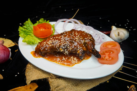 grilled chicken leg with sauce and vegetables on a black background.の写真素材