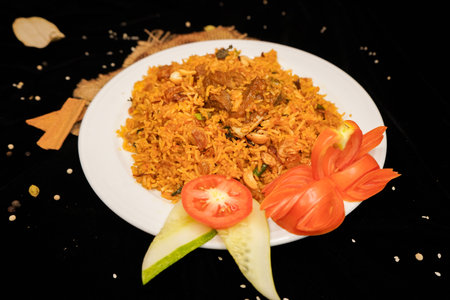 fried rice with meat and vegetables on a white plate on a black backgroundの写真素材