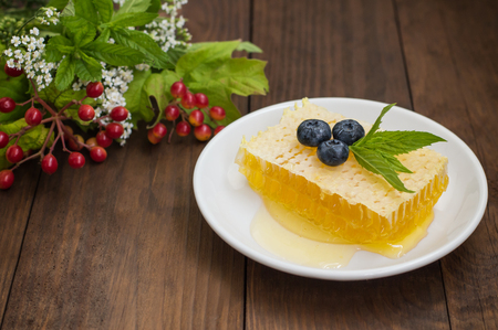 Honeycomb with blueberries and mint. Wooden backgroundの写真素材