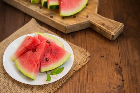 Watermelon sliced slices with a sprig of mint on a wooden backgroundの写真素材
