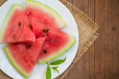 Watermelon sliced slices with a sprig of mint on a wooden backgroundの写真素材