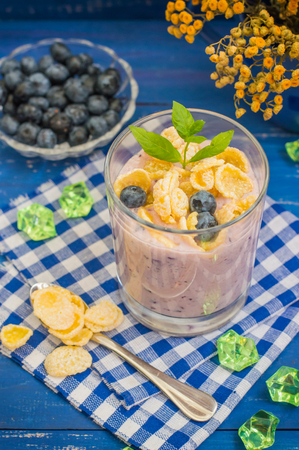 Blueberry Yogurt, cereal and a sprig of mint. Wooden blue backgroundの写真素材