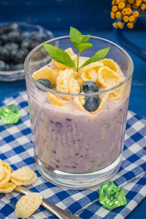 Blueberry Yogurt, cereal and a sprig of mint. Wooden blue backgroundの写真素材