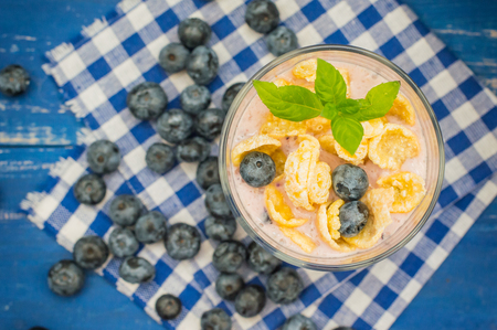 Blueberry Yogurt, cereal and a sprig of mint. Wooden blue backgroundの写真素材