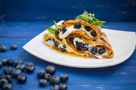 Pancakes with blueberries, whipped cream and a sprig of mint and lemon balmの写真素材