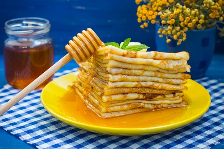 Pancakes with honey, butter and a sprig of mint and lemon balmの写真素材