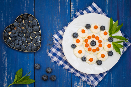 Blueberries and buckthorn laid out in the shape of a heart with cream meringueの写真素材