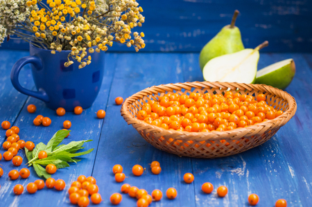 Crumbled buckthorn with basket on the table. Wooden backgroundの写真素材
