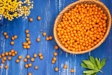 Crumbled buckthorn with basket on the table. Wooden backgroundの写真素材