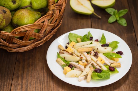 Chicken salad, pears, dried gooseberries and currants, cheese on basil leavesの写真素材