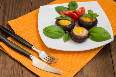Stuffed champignon quail eggs with basil and tomatoes. Wooden background.の写真素材