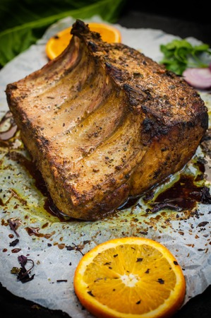 Baked pork ribs with sauce and basil on a black tableの写真素材