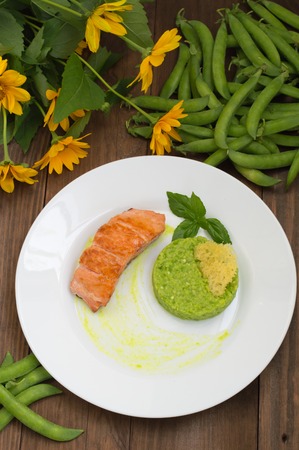 Grilled salmon steak with pea puree, cheese crisps and basil on a plate with the sauce.の写真素材