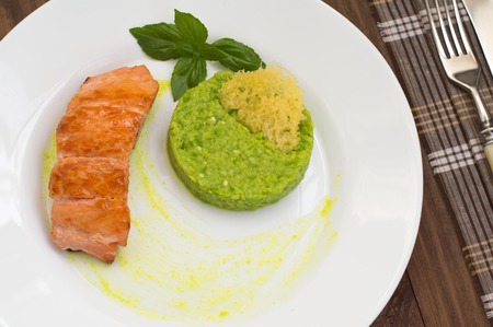 Grilled salmon steak with pea puree, cheese crisps and basil on a plate with the sauce.の写真素材