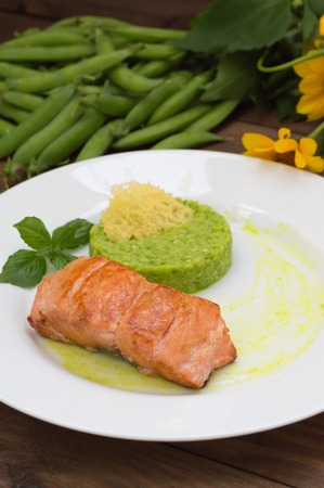 Grilled salmon steak with pea puree, cheese crisps and basil on a plate with the sauce.の写真素材