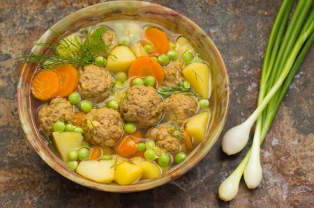 Soup with meatballs, carrots and peas.の写真素材