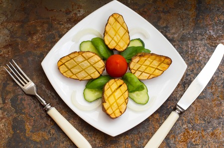 Baked potatoes with vegetables on the background color. Wooden tableの写真素材