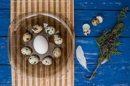Chicken and quail eggs on a dark transparent plate
