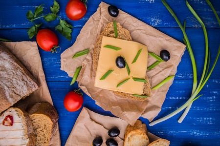 Sliced cheese with olives, radishes and herbs. On a wooden background. Top view.の写真素材
