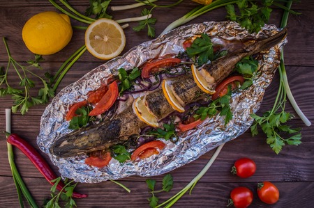 Pike baked with vegetables on the table. Wooden rustic background. Top viewの写真素材