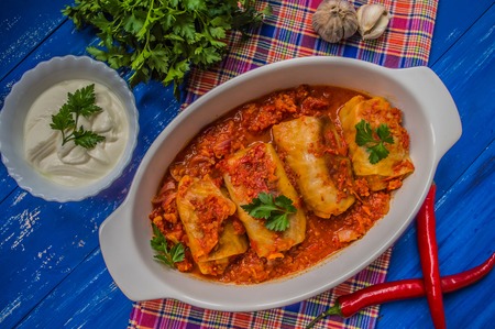 Dinner with cabbage rolls in tomato sauce decorated with parsley. Wooden blue rustic background. Top view.の写真素材