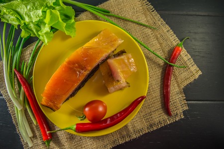 Pork fillet of smoked silver carp to beer on a yellow plate with greens. Top view. Black background of wood.の写真素材