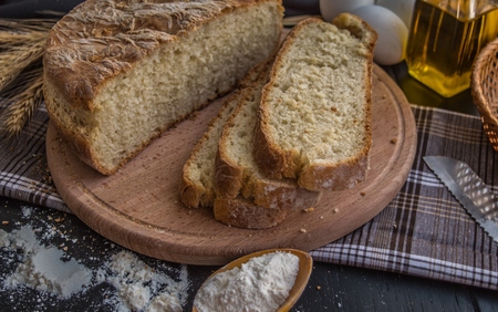 Freshly baked bread and baking ingredients. On a black wooden table