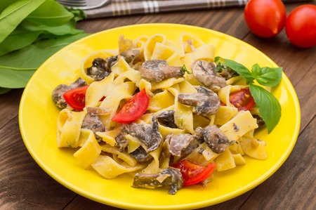 Fettuccine pasta in a creamy sauce with mushrooms on a plate on a wooden table. Horizontal top viewの写真素材