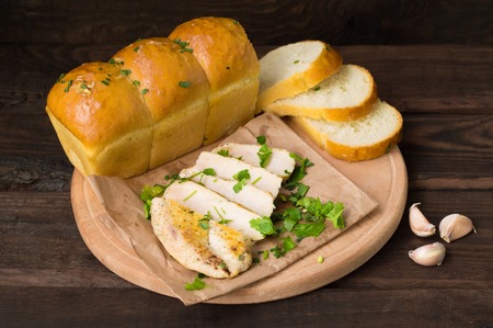 Garlic bread with fried chicken, greens and sauce on a wooden background. Top view. Close-upの写真素材
