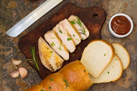 Garlic bread with fried chicken, greens and sauce on a wooden background